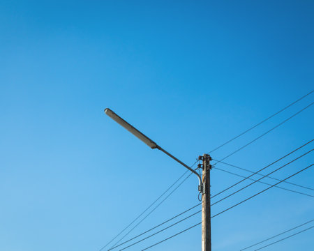 Electrical pole against the blue sky background. Street lamp.