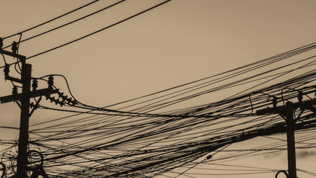 Silhouettes of electric poles and messy wires. Disorderly management. Industrial background. City life.の写真素材