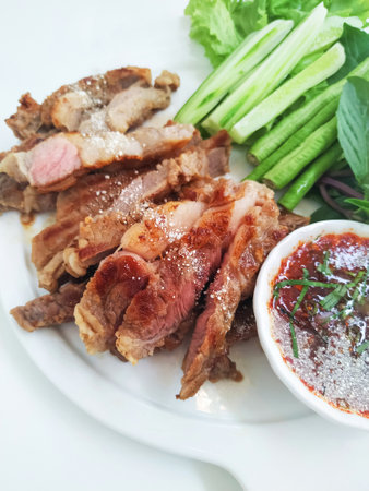 Sliced ââgrilled beef and vegetables with Thai spicy sauce served on a plate. Food menu.の写真素材
