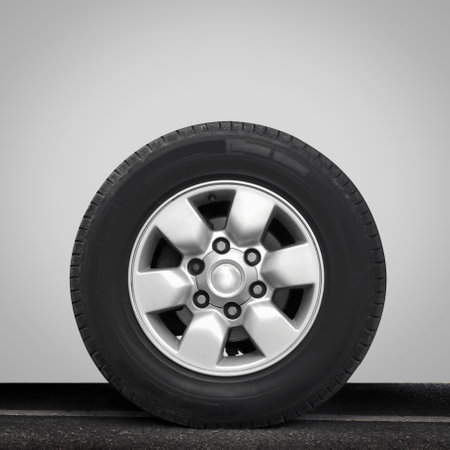 Old wheel and tire on asphalt road. Car part service. Auto garage repair shop.の写真素材
