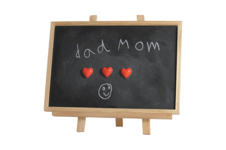 Child write with chalk on a blackboard with heart magnets to express for their parents. Love dad and mom. Happiness in the family.の写真素材