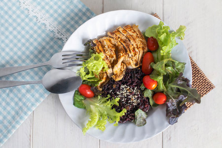 Healthy grilled chicken and riceberry with sesame. Serve with fresh salad and cherry tomatoes. Top view of healthy food on white table. Clean eating.の写真素材