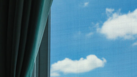 View of the sunny bright blue sky outside through the screened window and curtains in the room