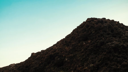 Peak of Rugged rock texture at the seashore against bright turquoise sky. Geological formation, potentially volcanic or basalt. Seascape adventure.の写真素材