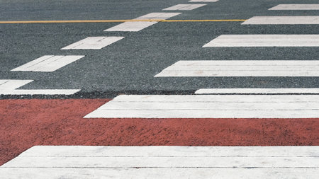 White zebra crossing lines and red bike lane on asphalt road. Urban street texture for background,...