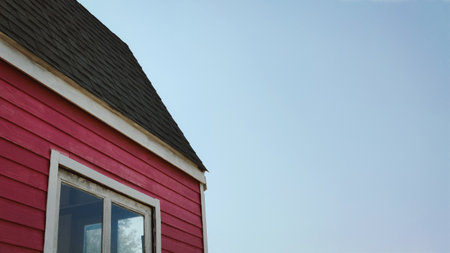 Minimal house exterior with red wooden wall and bright morning blue sky, modern rural architecture...
