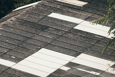 Old corrugated roof tile with repaired white panels, showing contrast of new and old materials,...