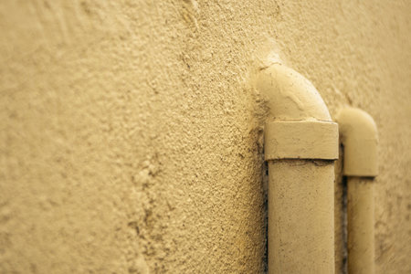 Close-up of yellow drain pipes on a rough textured wall, minimal industrial background suitable for design and architecture themes.の写真素材