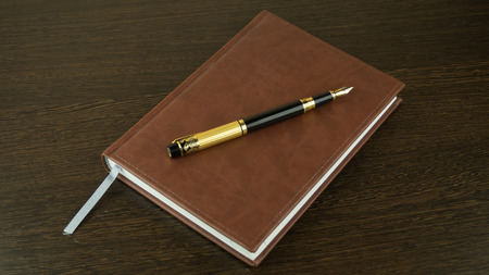 diary and fountain pen on a dark table backgroundの写真素材