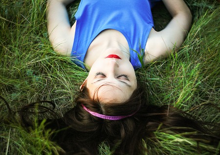 Beautiful girl lies on the grass backgroundの写真素材