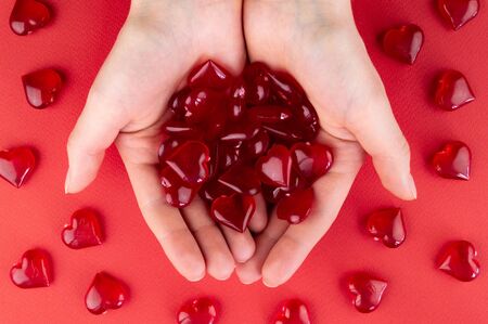 Figurines heart in hands as a symbol of love on red backgroungの写真素材