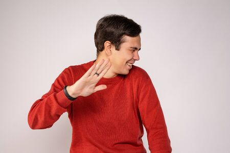 A young guy in a red sweater laughs. Portrait on gray backgroundの写真素材