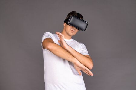A guy in virtual reality glasses is dancing. Future and modern technologies. Image on a gray...