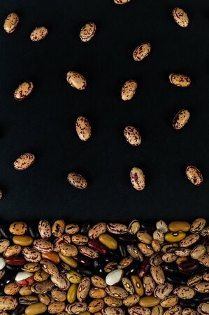 Different beans scattered on the table. Natural products on a dark background.