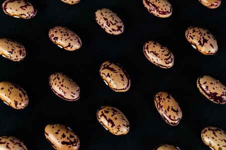Different beans scattered on the table. Natural products on a dark background.