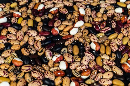 Different beans scattered on the table. Natural products on a dark background.