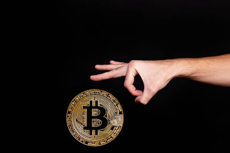 The symbol of the new popular cryptocurrency bitcoin with the image of hands on dark backgroundの写真素材