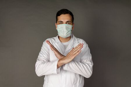 Portrait of a doctor in a medical gown clutching his head because of the number of patients with coronavirus.の写真素材