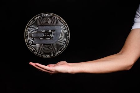 The symbol of the new popular cryptocurrency dash with the image of hands on dark background