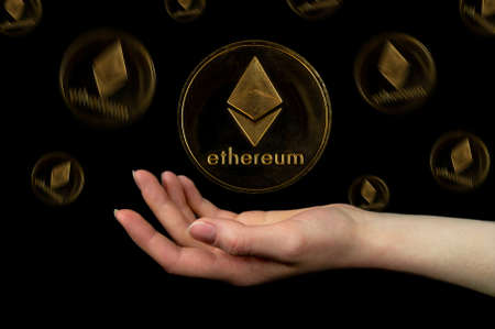 Elements of the ethereum cryptocurrency fall on the hand. Photo on a black backgroundの写真素材