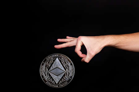 Elements of the ethereum classic cryptocurrency fall on the hand. black backgroundの写真素材