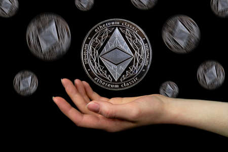 Elements of the ethereum classic cryptocurrency fall on the hand. black backgroundの写真素材