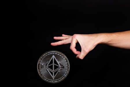 Elements of the ethereum classic cryptocurrency fall on the hand. black backgroundの写真素材