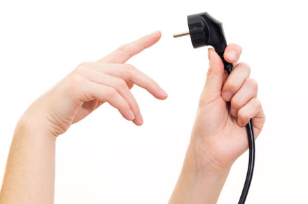 The concept girl holds a power cable plug in her hand. Image on a white backgroundの写真素材