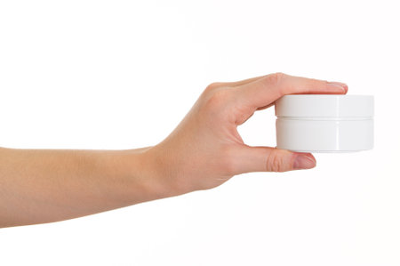The girl holds a white jar of cream on a white background. Image on a white backgroundの写真素材
