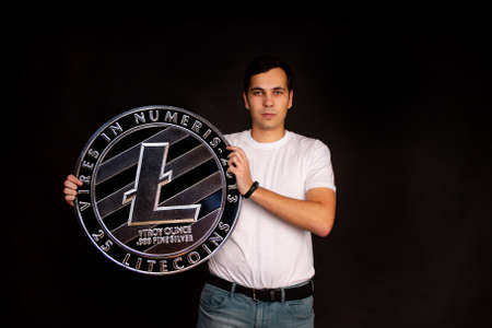 A man holds a litecoin coin in his hands as a symbol of technology. Image on black backgroundの写真素材