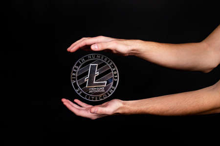 Litecoin coin and a man's hand on a black background. A symbol of technology and a new means of currency settlementの写真素材