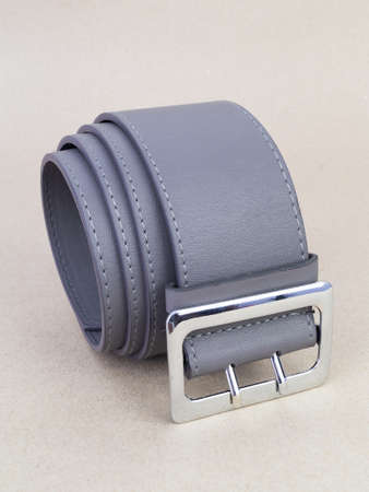 A leather belt with a clasp lies neatly on the table. background light paperの写真素材