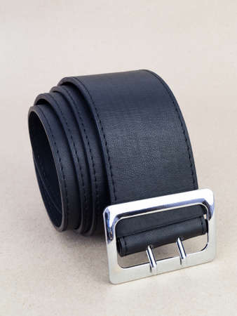 A leather belt with a clasp lies neatly on the table. background light paperの写真素材