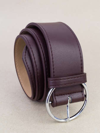 A leather belt with a clasp lies neatly on the table. background light paperの写真素材