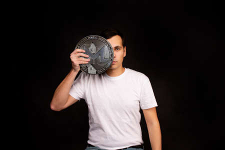 A man holds a monero coin in his hands as a symbol of technology. Image on black backgroundの写真素材
