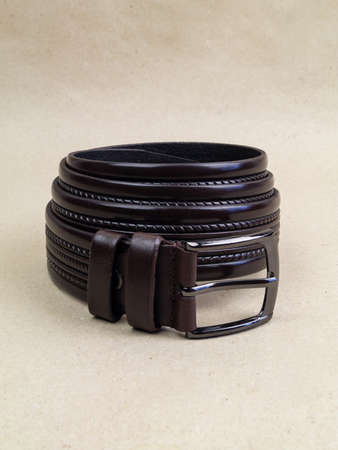 A leather belt with a clasp lies neatly on the table. background light paperの写真素材