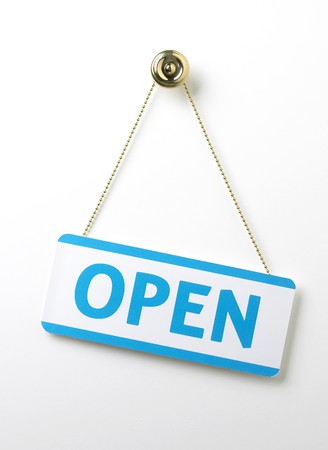 a process blue angled open door sign on a brass chain on a white backgroundの写真素材