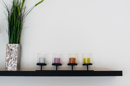 Decorative candle with flower vase on wooden shelf.の写真素材