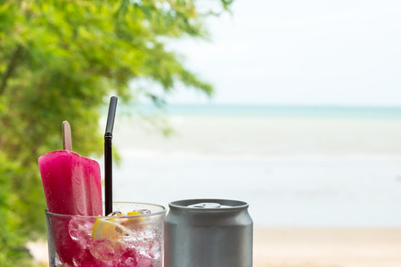 Red drink mixed soda with ice cream and lemon on blurred beach backgroundの写真素材