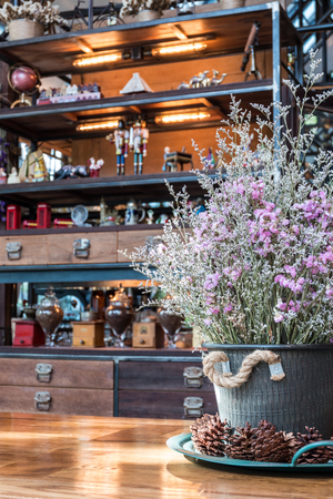 Close up dry Statice flower in pot on wooden table with blurred decorated shelves backgroundの写真素材