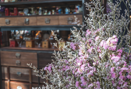 Close up dry Statice flower in pot on wooden table with blurred decorated shelves backgroundの写真素材