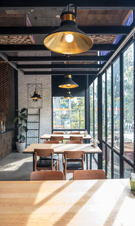 Close up of table and chair set in modern cafe minimalistic interior design with big window and hanging ceiling lampsのeditorial素材