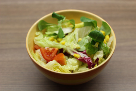 Fresh colourful mixed leaves salad with cherry tomatoes and corn in a bowl.の写真素材