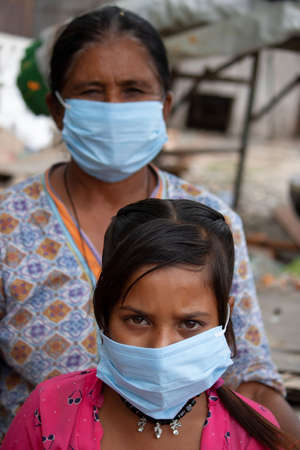 Dehradun, Uttarakhand/India- August 15 2020: Mother with her girl child wearing mask maintaining social distancing, facing camera.のeditorial素材