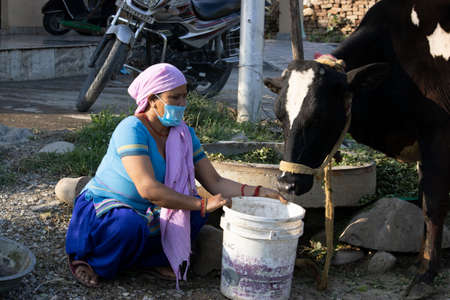 Dehradun, Uttarakhand/India - August 14 2020 : Indian woman washing clothes wearing mask .のeditorial素材