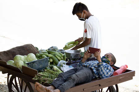 Dehradun, Uttarakhand/India - September 06 2020: A Boy selling vegetables on cart and his brother laying down on it.のeditorial素材