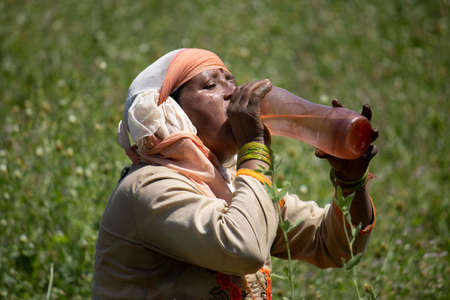Dehradun, Uttarakhand/India - September 10 2020:A Women drinking water while working in fields.のeditorial素材