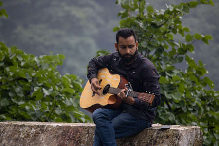 Dehradun, Uttarakhand/India-September 12 2020:A youngster playing guitar in beautiful hills.のeditorial素材