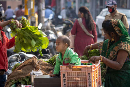 Dehradun, Uttarakhand/India-October 14 2020:A poor women selling vegetables on push cart with her cute little child in basket in India. High quality photoのeditorial素材