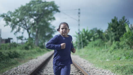 Indian Kid running on the railway track in the Himalayan range of India, greenery in the background. Physical fitness training. High-quality photoの写真素材